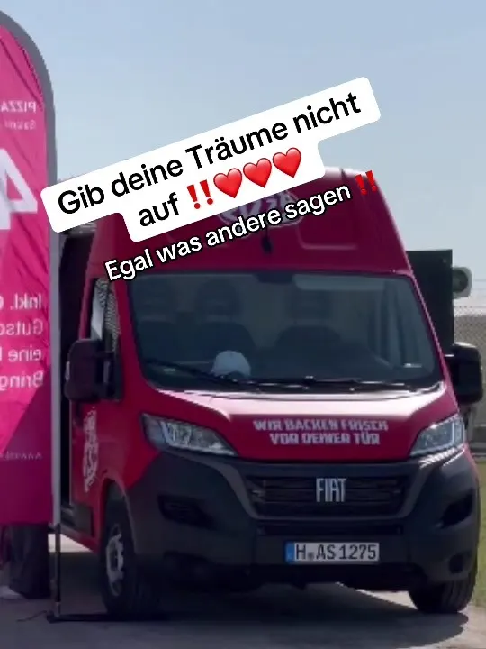 Der rote Pizza-Van auf dem Platz, darüber der Text „Gib deine Träume nicht auf“