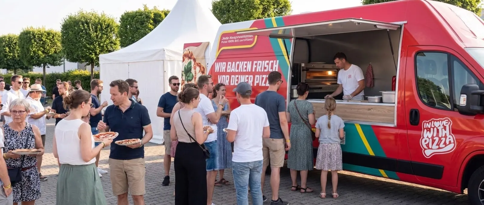 Der rote Pizza-Van hält in einer Wohnstraße, Gäste nehmen ihre Pizza direkt am Wagen entgegen